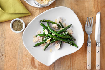 Plate with delicious green beans, almond and mushrooms on table