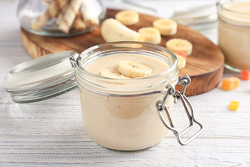 Glass jar with delicious banana smoothie on wooden table