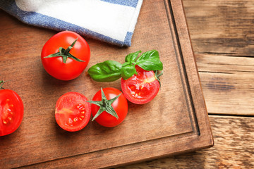 Board with fresh cherry tomatoes on wooden table