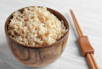 Bowl with brown rice on wooden table