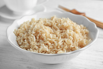 Bowl with brown rice on wooden table