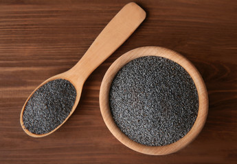 Ripe poppy seeds in spoon and bowl on wooden background