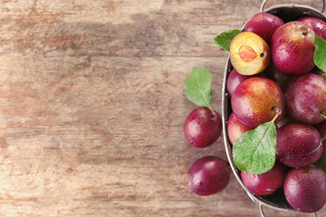 Basket with ripe plums on wooden table