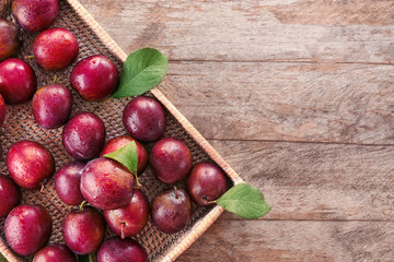 Fresh ripe plums on wicker tray