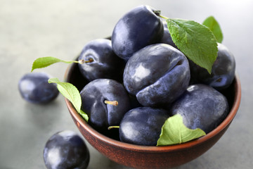 Bowl with ripe plums on table