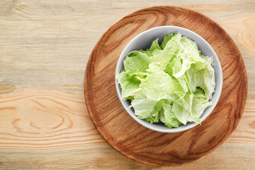 Bowl with fresh green cabbage leaves on table