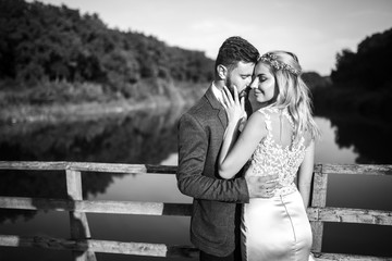 Stylish couple of happy newlyweds posing in the park on their wedding day. Perfect couple bride, groom posing and kissing.black and white.

