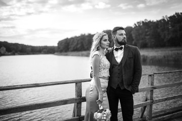 Stylish couple of happy newlyweds posing in the park on their wedding day. Perfect couple bride, groom posing and kissing.black and white.

