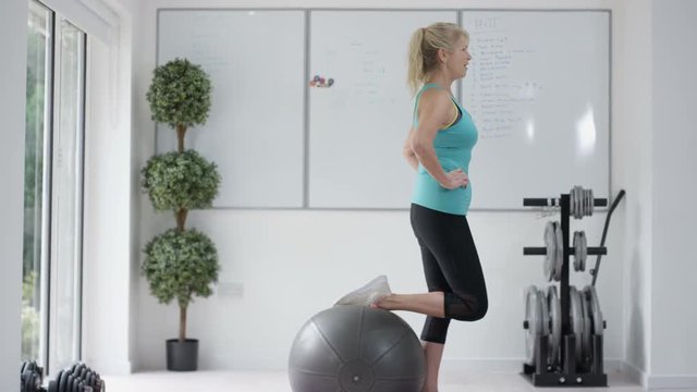  Healthy mature woman working out with fitness ball in the gym