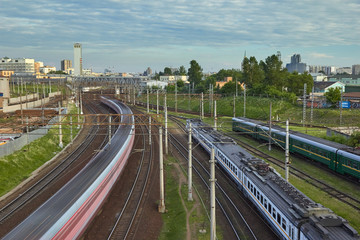 Cityscape with many railway tracks at the foreground and movement of commuter passenger train