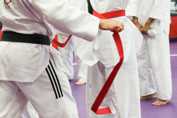 Martial Arts Teach putting on Student's Red Belt