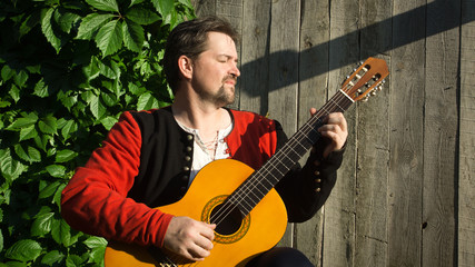 Adult man playing guitar in summer garden