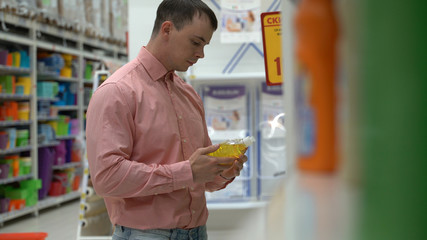 young guy buys liquid soap in a store or supermarket.