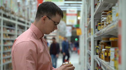 a young guy chooses a honey in a store.