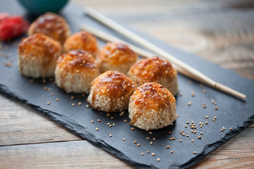 Japanese cuisine. Baked sushi with crab meat and cheese on a stone slab in a dark wood background