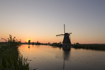 Fototapeta na wymiar Travelling Concepts and Ideas. UNESCO Heritage Dutch Windmills In Front of The Canal and Sun at Kinderdijk Located in Traditional Village in Holland, The Netherlands.