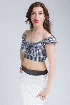 Portrait of Sensual Attractive Caucasian Brunette Model Posing in White Pleated Skirt and Tartar Bra. Vertical Image