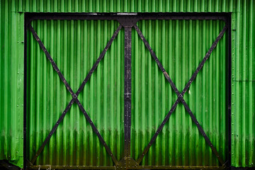 Old green corrugated iron gate of a barn  in Norway with black beams
