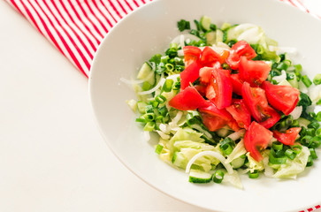 Georgian salad tomatoes cucumbers, onions, on white table red napkin striped