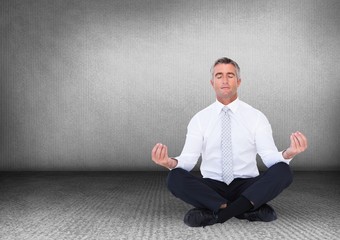 Business man meditating against grey wall