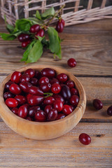 Fresh cornel berries on a wooden background.