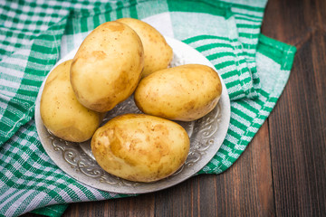 Raw potatoes on a brown wooden background