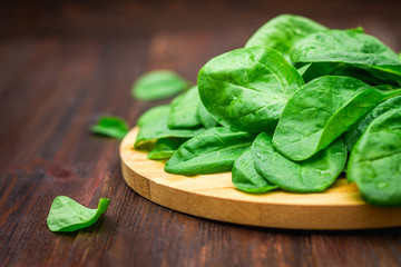 Fresh juicy spinach leaves on a wooden brown table. Natural products, greens, healthy food, vitamins.