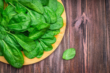 Fresh juicy spinach leaves on a wooden brown table. Natural products, greens, healthy food,...