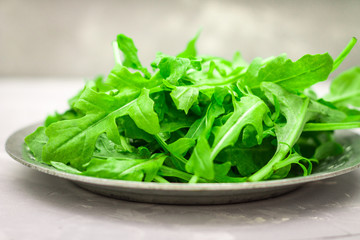Fresh juicy leaves of arugula on a light concrete background.