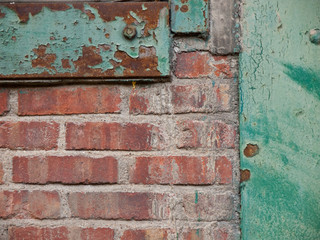 Close-up of a brick wall with green rusted metal panels