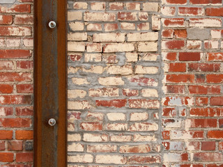 Multicolor brick wall with rusted metal beam and bolts