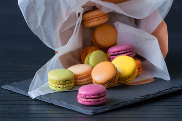 French macaroons. Craft box filled with macaroons. Dropped from gift box with colorful macarons on the black background. Rainbow.