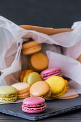 Colorful french macaroons. Craft box filled with macaroons. Dropped from gift box with colorful macarons on the black background. Rainbow.