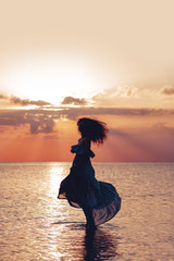 Elegant woman dancing on water. Sunset and silhouette