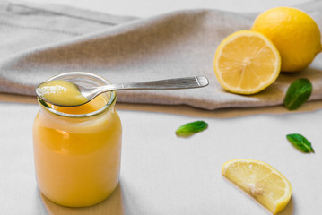 Lemon curd cream in a glass jar against white background