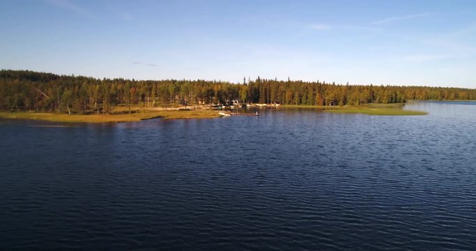 Northern lake, Cinema 4k aerial view just above the water level on lake pyhajarvi, revealing a beach full of row boats and kayaks, in arctic taiga wilderess of Lapland, in Lappi, Finland