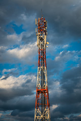 Mobile network antenna tower with cloudy sky in the background
