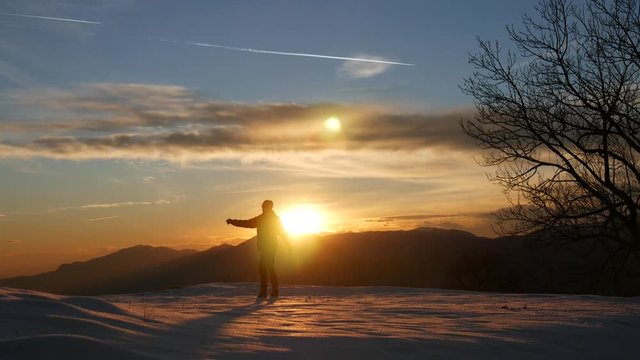 Turista gioisce del tramonto sulla neve in montagna