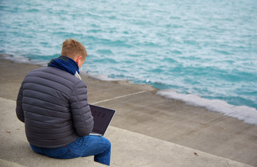 A young man is working on the sidewalk near lake