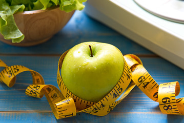 Green apple with weight scale and measuring tape for the healthy diet slimming . Diet and Healthy...