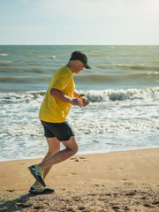 The man in the baseball cap and yellow shirt performs a workout on the ocean.