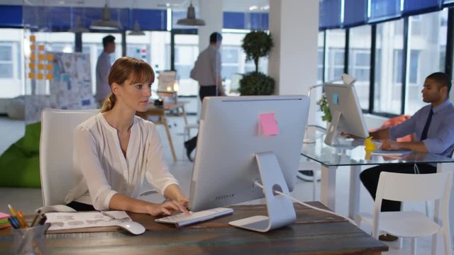 Business group in modern office, focus on woman working on computer.