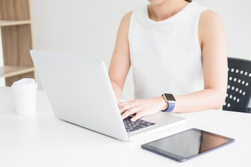 Attractive women in casual business sitting at a table working on her laptop computer at home office in front of a window.