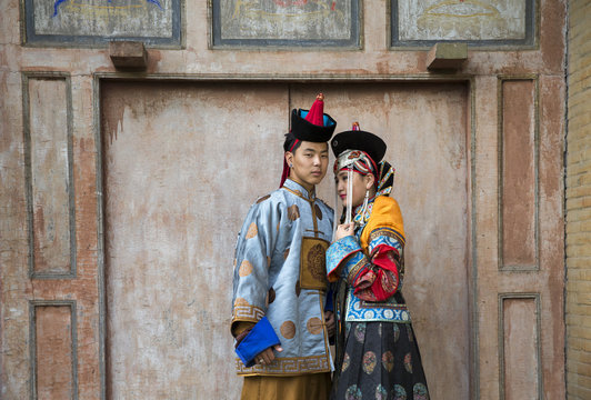 mongolian couple in traditional 13th century style outfit walking near old temple