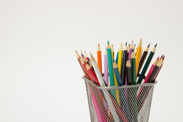 A group of colored pencils in a writing-glass on a white background