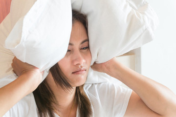 Closeup woman covering ears with pillow, noise problem