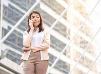 Portrait young Asian businesswoman holding smart phone in formal suit at the modern city, vintage tone