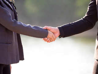 Shaking hands of business man and business woman over the nature blurred background