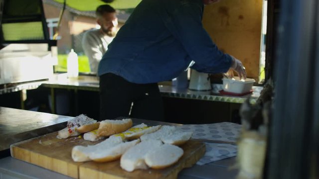  Street food vendor making hot dogs for customers at summer festival