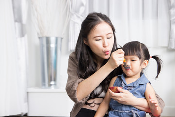 Little Asian girl eating fruit from mother feeding.